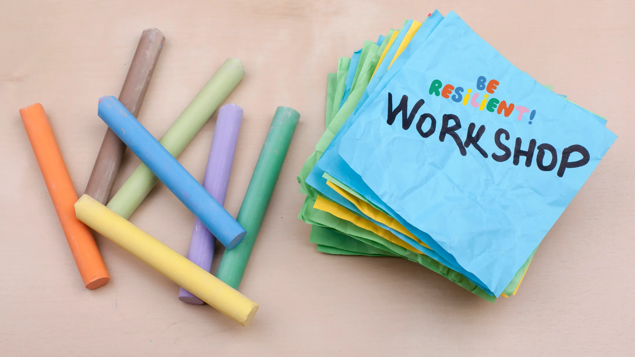 Bunte Kreidestücke neben Haftnotizen mit der Aufschrift „Be resilient! Workshop“
