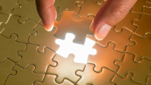 Das fehlende Puzzleteil des goldenen Puzzles wird ruhig und präzise mit zwei Fingern in eine leuchtende letzte Lücke eingesetzt